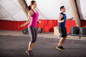 Young man and woman jumping ropes as part of their workout in a gym